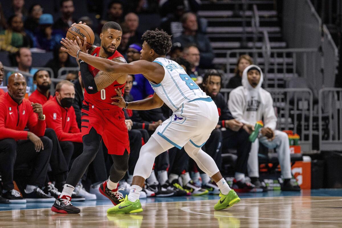 Portland Trail Blazers guard Damian Lillard (0) is guarded by Charlotte Hornets guard Dennis Smith Jr. (8) during the first half of an NBA basketball game Wednesday, Nov. 9, 2022, in Charlotte, N.C. (AP Photo/Scott Kinser)