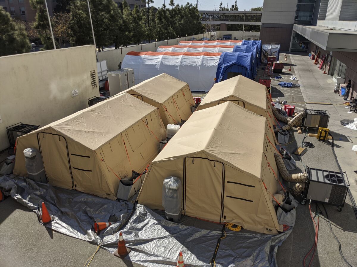 FILE - In this Monday, March 30, 2020, file photo, triage tents are deployed for a possible surge of emergency COVID-19 patients outside of the Los Angeles County + USC Medical Center in Los Angeles. A health official in California's third largest county is urging hospitals to cancel elective surgeries and implement plans for an onslaught of COVID-19 patients, as intensive care units fill up statewide amid spiking virus cases. Dr. Carl Schultz says ambulances have been waiting for hours to unload patients because Orange County emergency rooms are so backed up. (AP Photo/Damian Dovarganes, File)