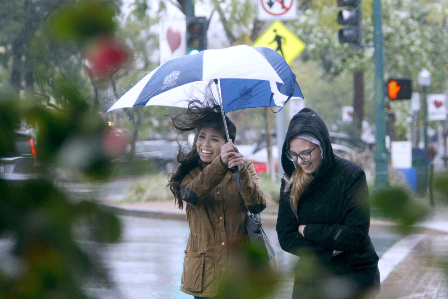 Felicia Schliewe, 31 of Highland Park, left, and Daniella Langley, 24 of Lake View Terrace, get hit by a gust of wind as they walk on a rainy afternoon on Honolulu Avenue and Ocean View Avenue in Montrose, on Friday, Feb. 17, 2017. A massive storm hit the Southland over the weekend.
