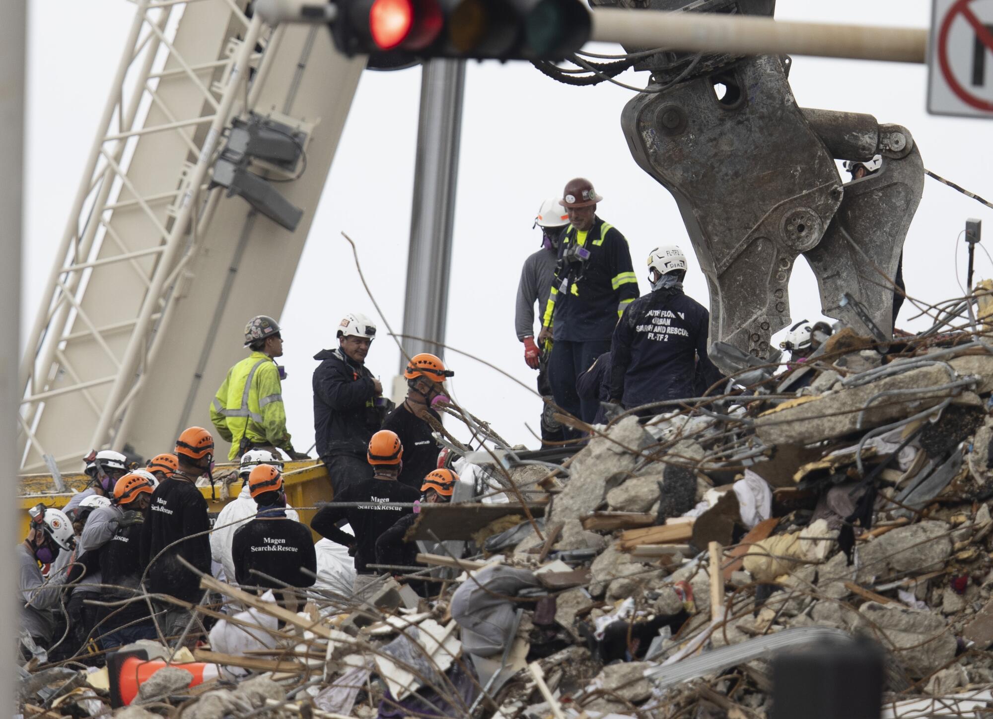 People in helmets gather atop rubble.