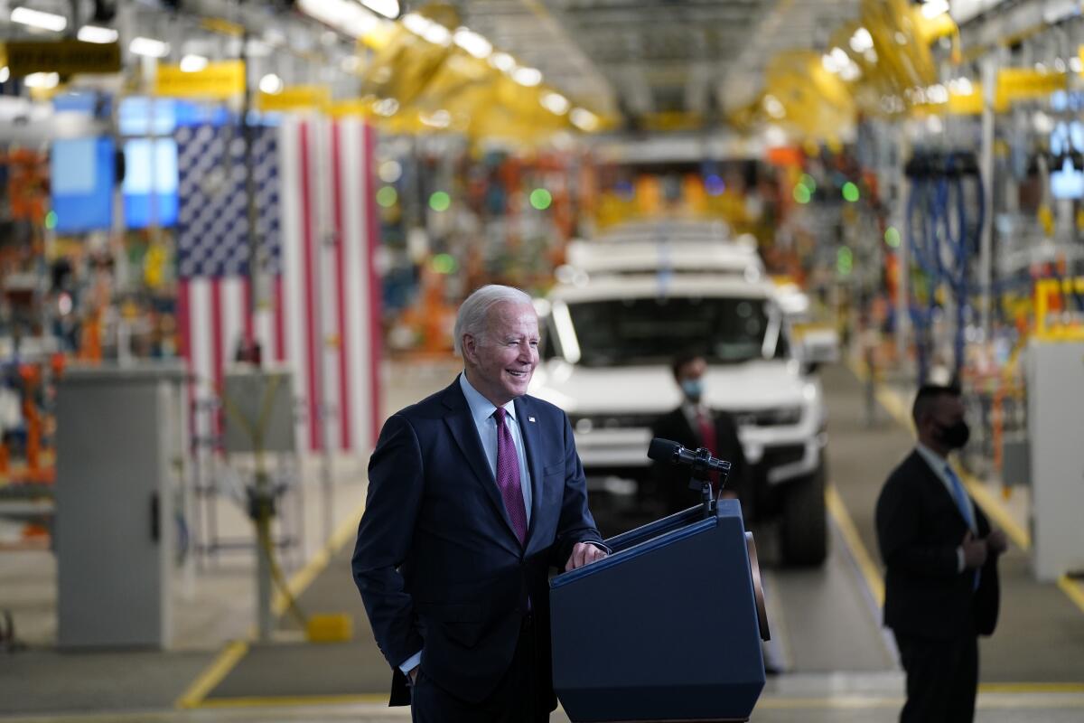President Biden stands at a lectern at a car factory.