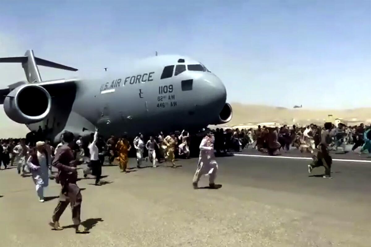 Hundreds of people run alongside a U.S. Air Force C-17 transport plane