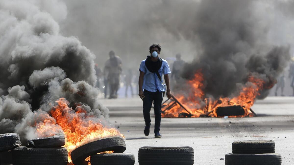 A masked protester walks between burning barricades in Managua, Nicaragua, on April 20.