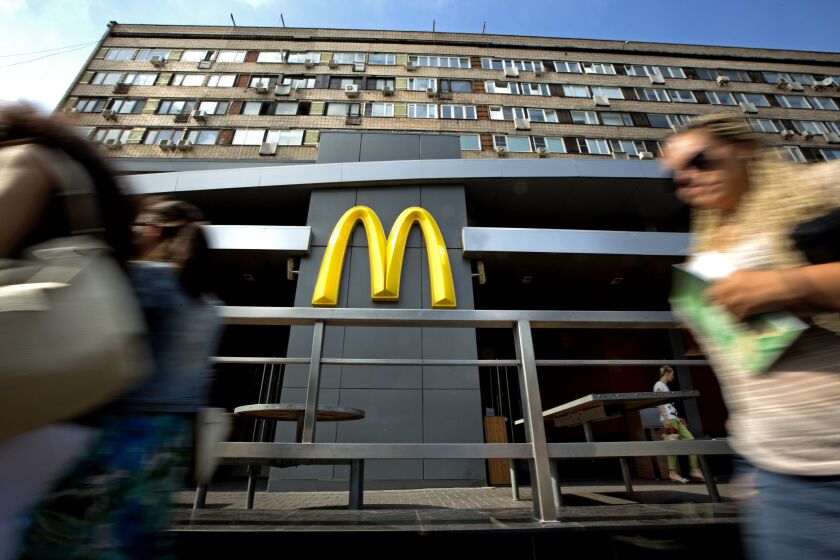 People walk past the oldest of Moscow's McDonald's outlets which was opened in 1990, and closed in 2014.