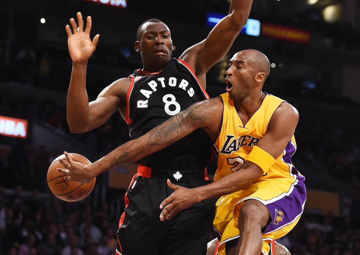 Lakers guard Kobe Bryant wraps a pass around Raptors center Bismack Biyombo after a drive down the lane.