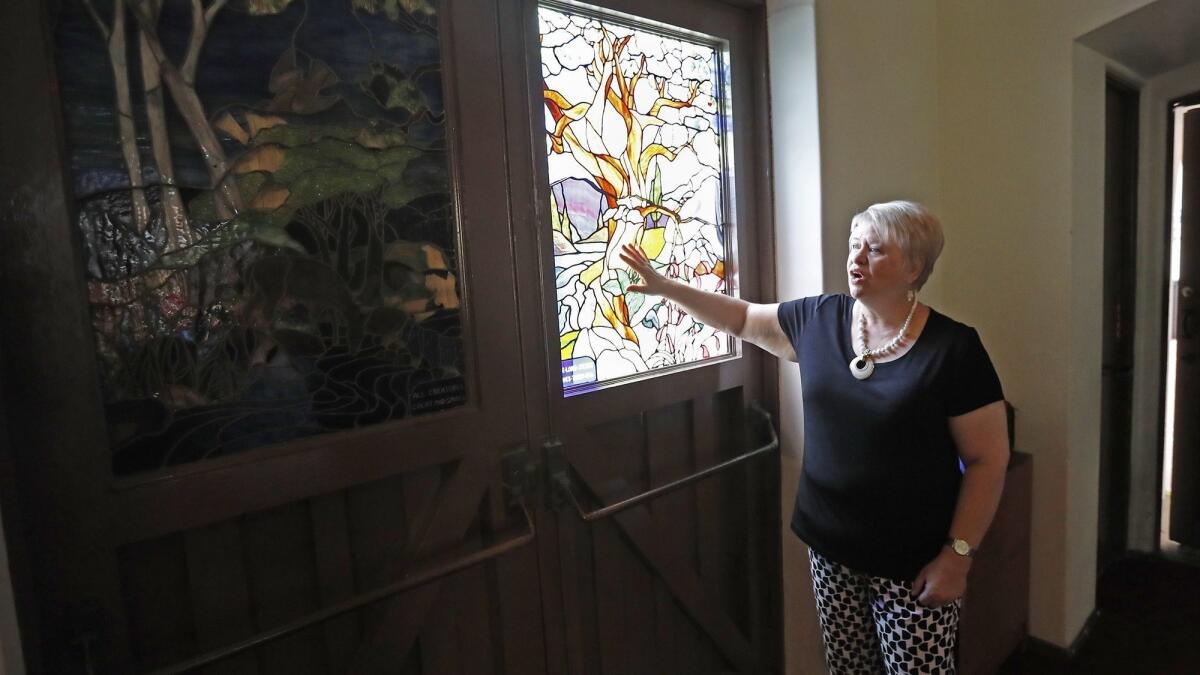 Joy Price, pastor of Christ Church by the Sea in Newport Beach, surveys vandalism damage to stained-glass windows at the main entrance to the church’s sanctuary.