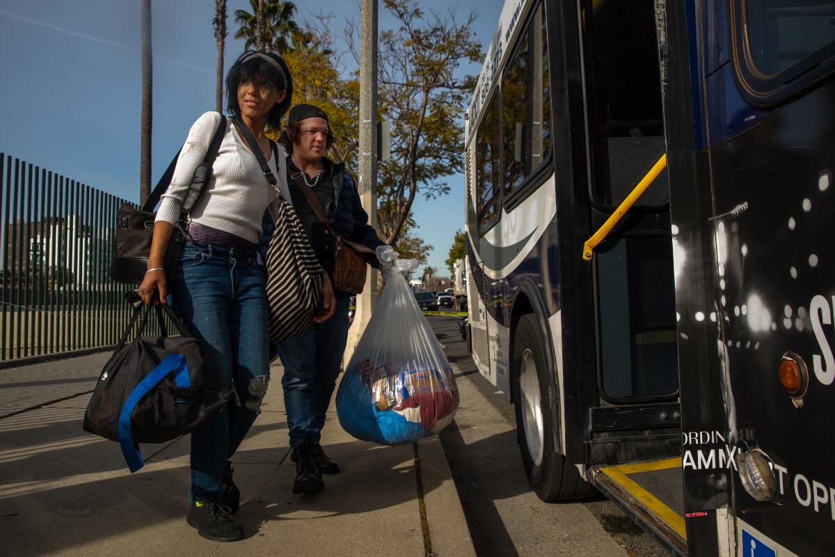 Courtney Astoria, 30, left, and Steve Miller, 36, step on a bus to move from the street to a motel
