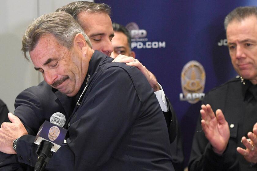 Los Angeles Mayor Eric Garcetti and LAPD Chief Charlie Beck embrace, while First Assistant Chief Michel Moore, right, applauds during a news conference Friday, Jan. 19, 2018, in Los Angeles, after Beck announced his retirement effective June 27. (John McCoy, Los Angeles Daily News/SCNG)/Los Angeles Daily News via AP)