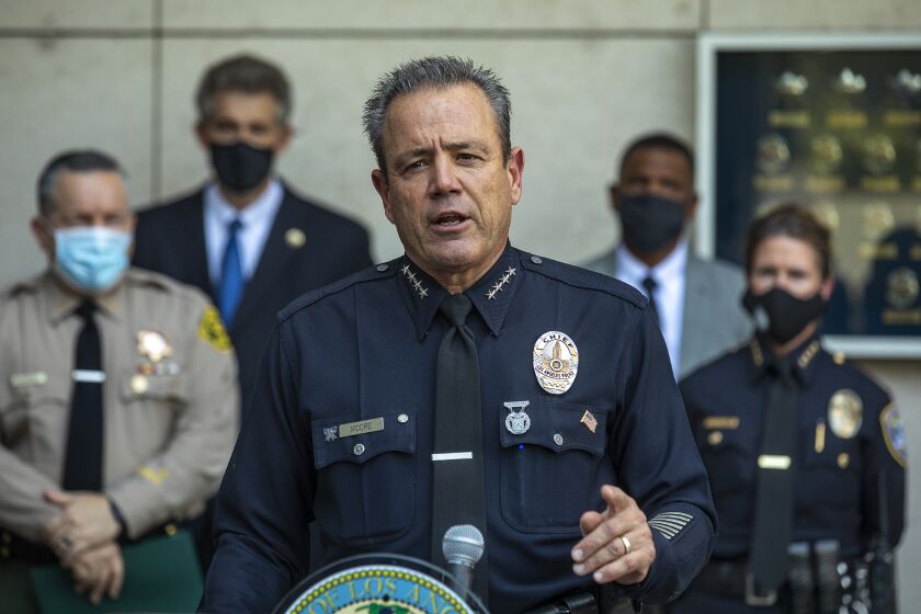 LOS ANGELES, CA - AUGUST 26, 2020: LAPD Chief Michel Moore addresses the media during a press conference held outside of LAPD Headquarters in downtown Los Angeles, announcing significant crime arrests made by the multi-agency SAFELA Task Force, which was formed to investigate crimes that occurred during protests and demonstrations in Los Angeles back in May and June. The LAPD has arrested 14 people as a result. At left is Los Angeles County Sheriff Alex Villanueva, 2nd from left is David Singer, U.S. Marshall for the Central District of California, and at right is Cynthia Renaud, Chief of the Santa Monica Police Dept. (Mel Melcon / Los Angeles Times)