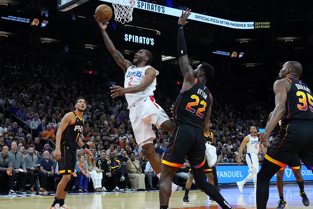 Clippers forward Kawhi Leonard beats Suns defenders for a right-handed layup.
