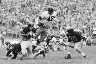 FILE - Southern California fullback C.R. Roberts (42) leaps over a California defender during the first half of a college football game Oct. 22, 1955, in Berkeley, Calif. California's Hugh Maguire (20) is at right. Roberts, whose record-setting performance helped USC beat Texas in a 1956 road game played in the segregated state, has died. He was 87. Roberts died of natural causes Tuesday, July 11, 2023, in Norwalk, Calif., the university said Wednesday. (AP Photo/Clarence Hamm, File)