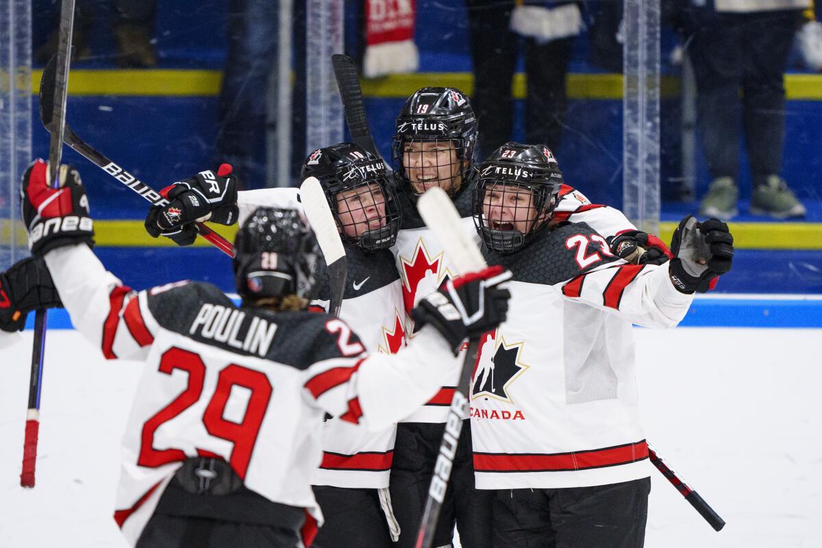 Canadian players hug and raise sticks and arms.