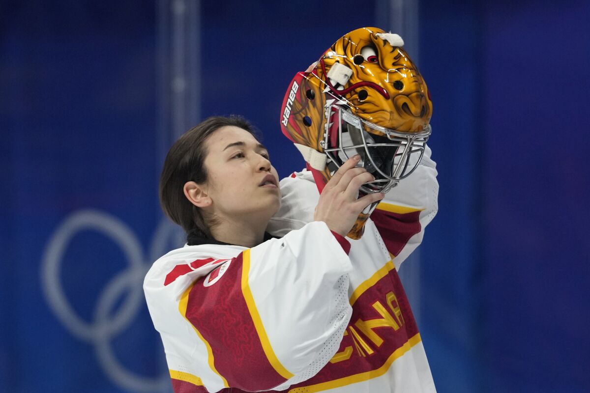 China goalkeeper Zhou Jiaying puts on her helmet during a preliminary round women's hockey game against Denmark at the 2022 Winter Olympics, Friday, Feb. 4, 2022, in Beijing. (AP Photo/Petr David Josek)