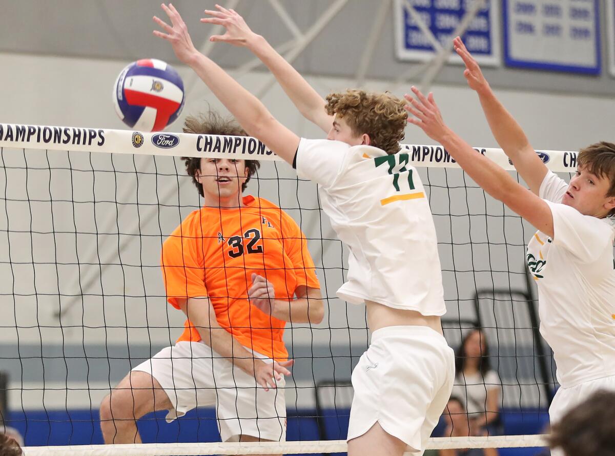 Huntington Beach's Nick Ganier Jr. (32) puts a kill past the block of Mira Costa's Wyatt Davis (11).