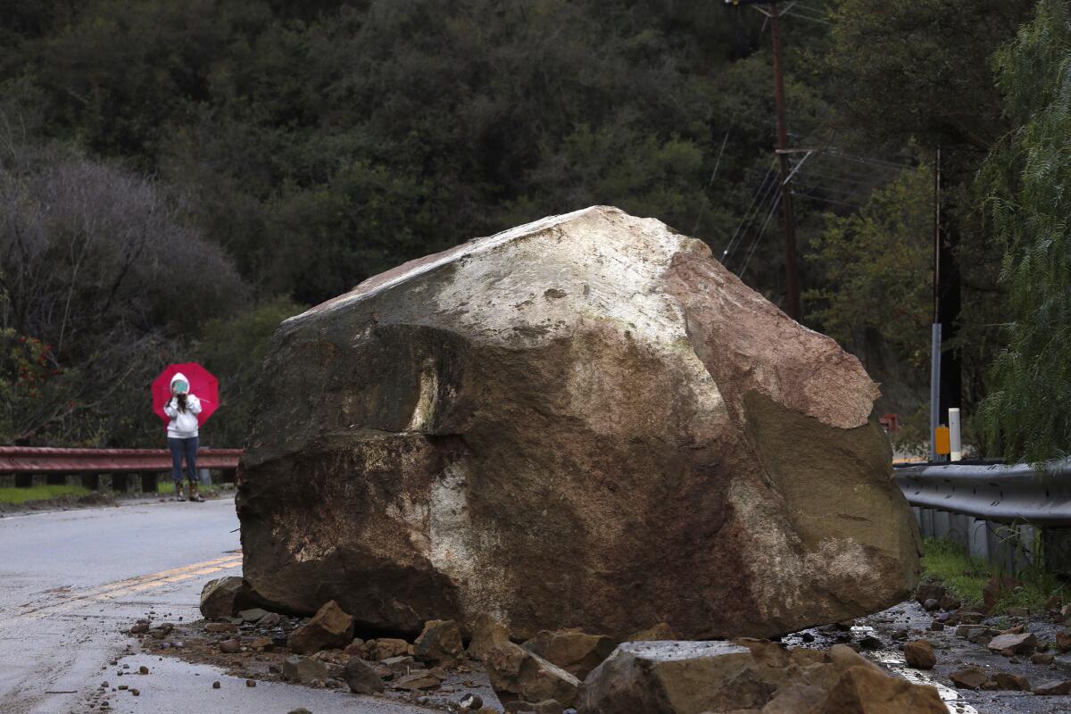 Gina Picciolo takes a picture on Monday of a boulder that fell onto Topanga Canyon Boulevard.