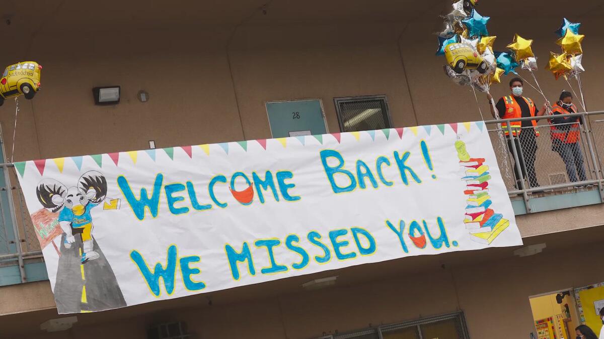 A handpainted banner at a school reads "Welcome back! We missed you."