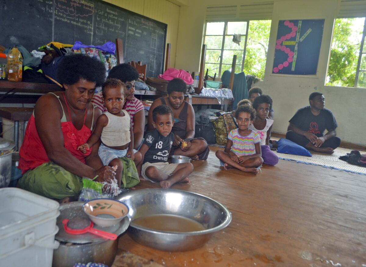 Families from Wainiveidilo settlement prepare their lunch at a school used as an evacuation center in Navua, Fiji.