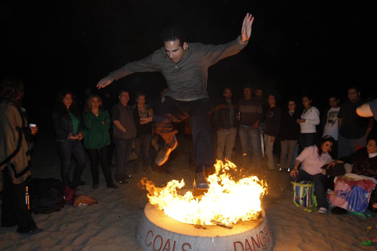 John Sami, 37, of Newport Beach, jumps over a fire in a a traditional part of Persian New Year celebrations on March 19, 2013, at Corona del Mar State Beach.