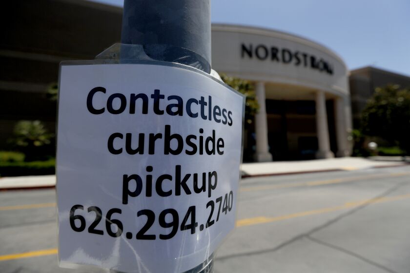 ARCADIA, CALIF. - MAY 27, 2020. A sign taped to a lightpost tells customers about curbside pickup services at a store in the Santa Anita Mall in Arcadia on Wednesday, May 27, 2020. Stores remained mostly closed despite restrictions being lifted for for in-store shopping throughout California. (Luis Sinco/Los Angeles Times)
