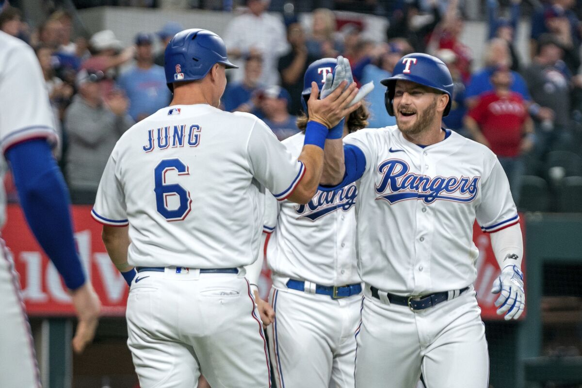 Texas Rangers' Robbie Grossman, right, is congratulated by Josh Jung after hitting a three-run home run that scored Jung and Jonah Heim, center, during the fourth inning of an opening day baseball game against the Philadelphia Phillies, Thursday, March 30, 2023, in Arlington, Texas. (AP Photo/Jeffrey McWhorter)