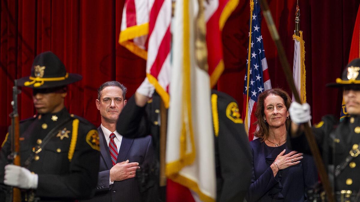 Orange County District Attorney Todd Spitzer and his wife, Jamie, place their hands over their hearts during Spitzer's swearing-in as district attorney.