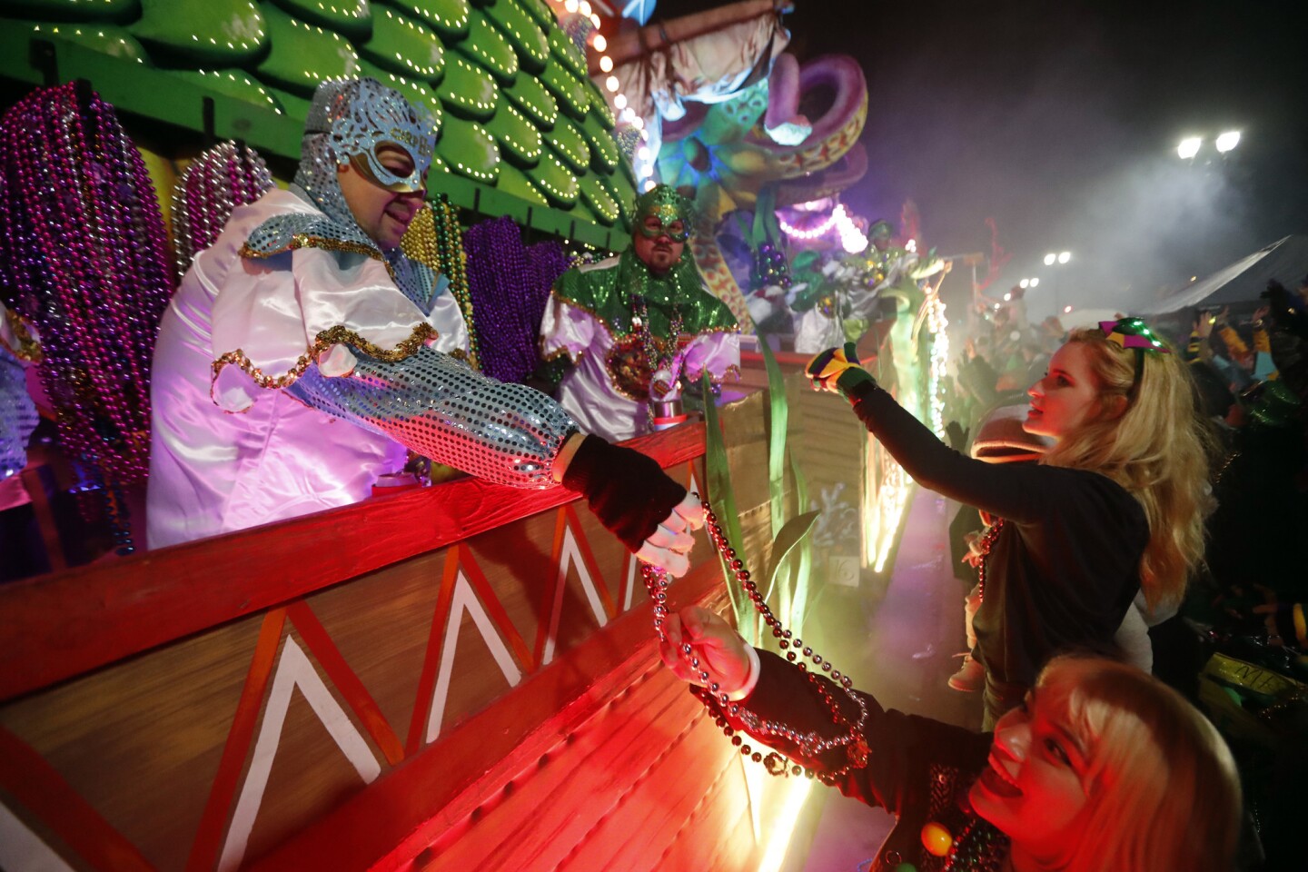 Float riders hand beads to the crowd as the Krewe of Orpheus parade rolls in New Orleans on Monday.