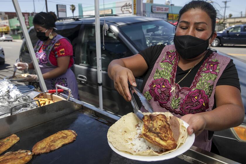 Los Angeles, CA - June 12: Adela Ruiz makes chile relleno taco. Oaxacan migrants make traditional meals and give them out for free on side-walk in front of flower shop Yeaj Yalhalhj on Saturday, June 12, 2021 in Los Angeles, CA. (Irfan Khan / Los Angeles Times)