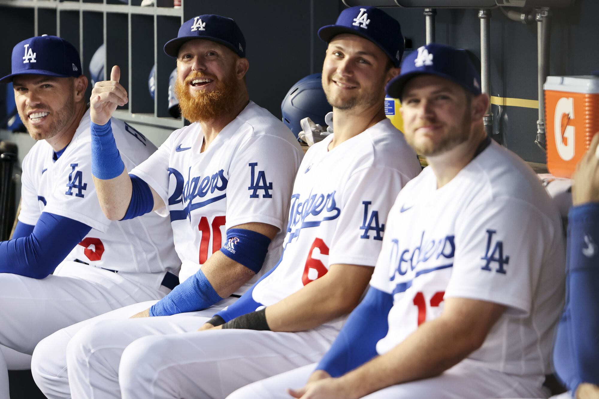 Dodgers teammates (from left) Freddie Freeman, Justin Turner, Trea Turner and Max Muncy sit in the dugout.