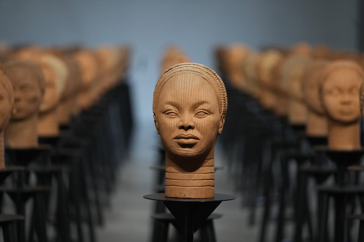 Brown sculptures of heads on pedestals in rows