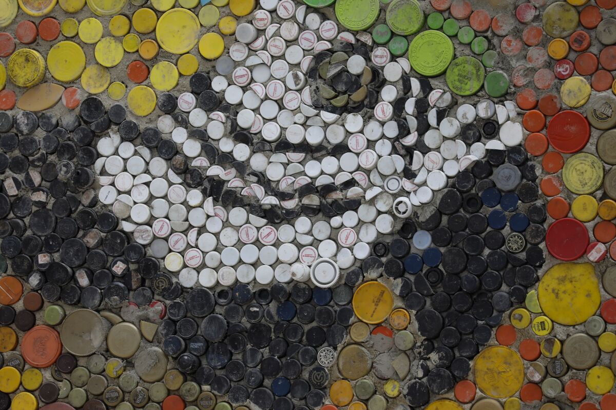 Plastic bottle caps form the face of a macaw within a large mosaic by Venezuelan artist Oscar Olivares in El Hatillo on the outskirts of Caracas, Venezuela, Thursday, Jan. 30, 2020. Olivares, 23, is using thousands of plastic bottle caps to create this mural which he started when he was just 14. (AP Photo/Ariana Cubillos)