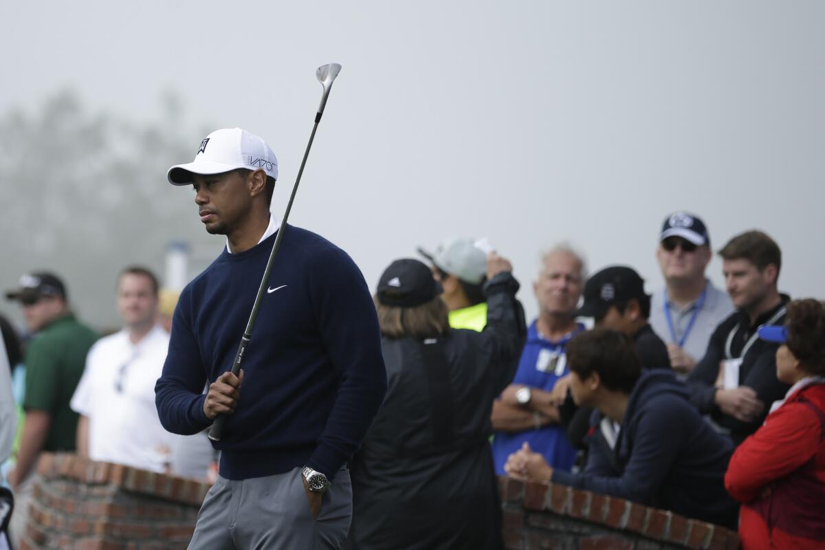 Tiger Woods takes a few one-arm swings Thursday during a fog delay at the first round of the Farmers Insurance Open.