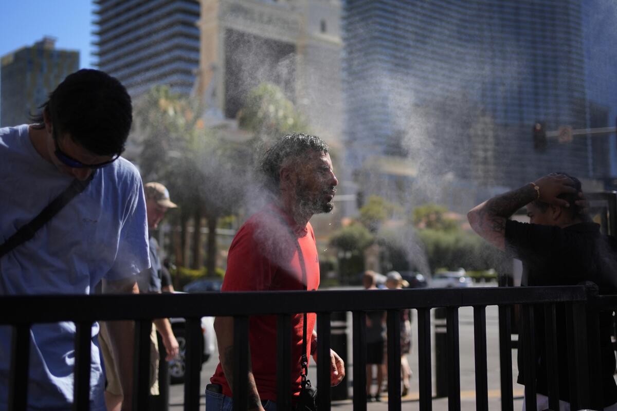 ARCHIVO - Gente que se refresca en rociadores de agua en el Strip de Las Vegas,