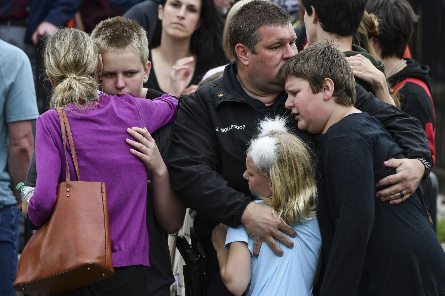 A police officer hugs his kids after they were evacuated to the Recreation Center at Northridge after a shooting at STEM School Highlands Ranch on May 7, 2019, in Highlands Ranch, Colo.