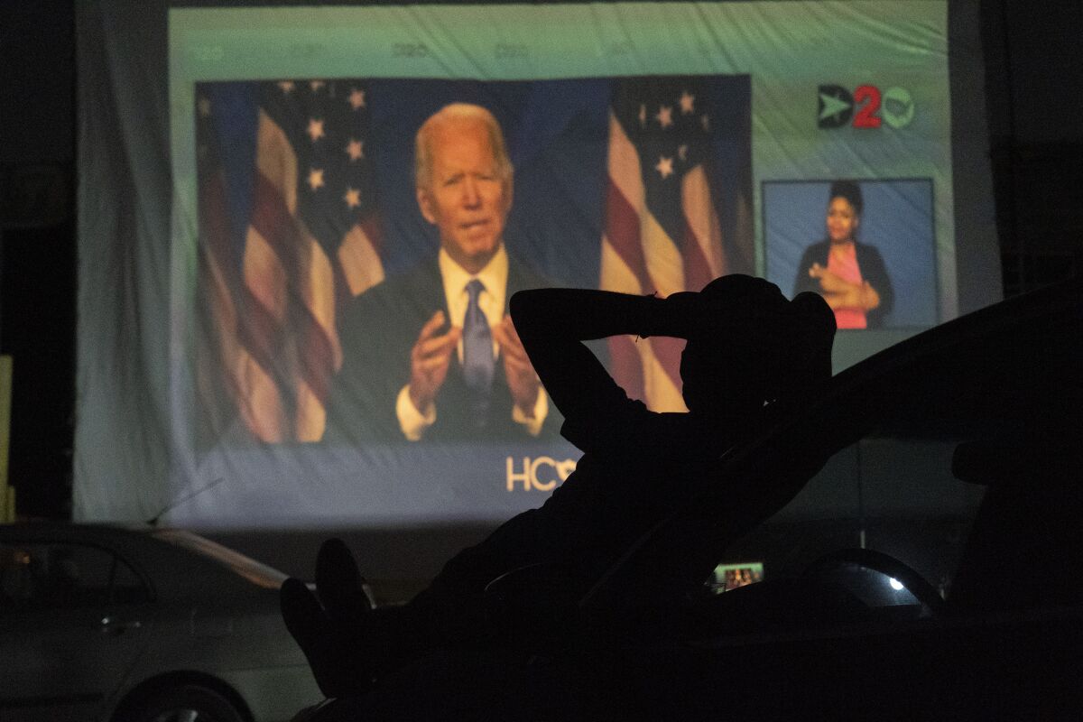 A Texas supporter watches Joe Biden speak on a large screen at a Houston drive-in.
