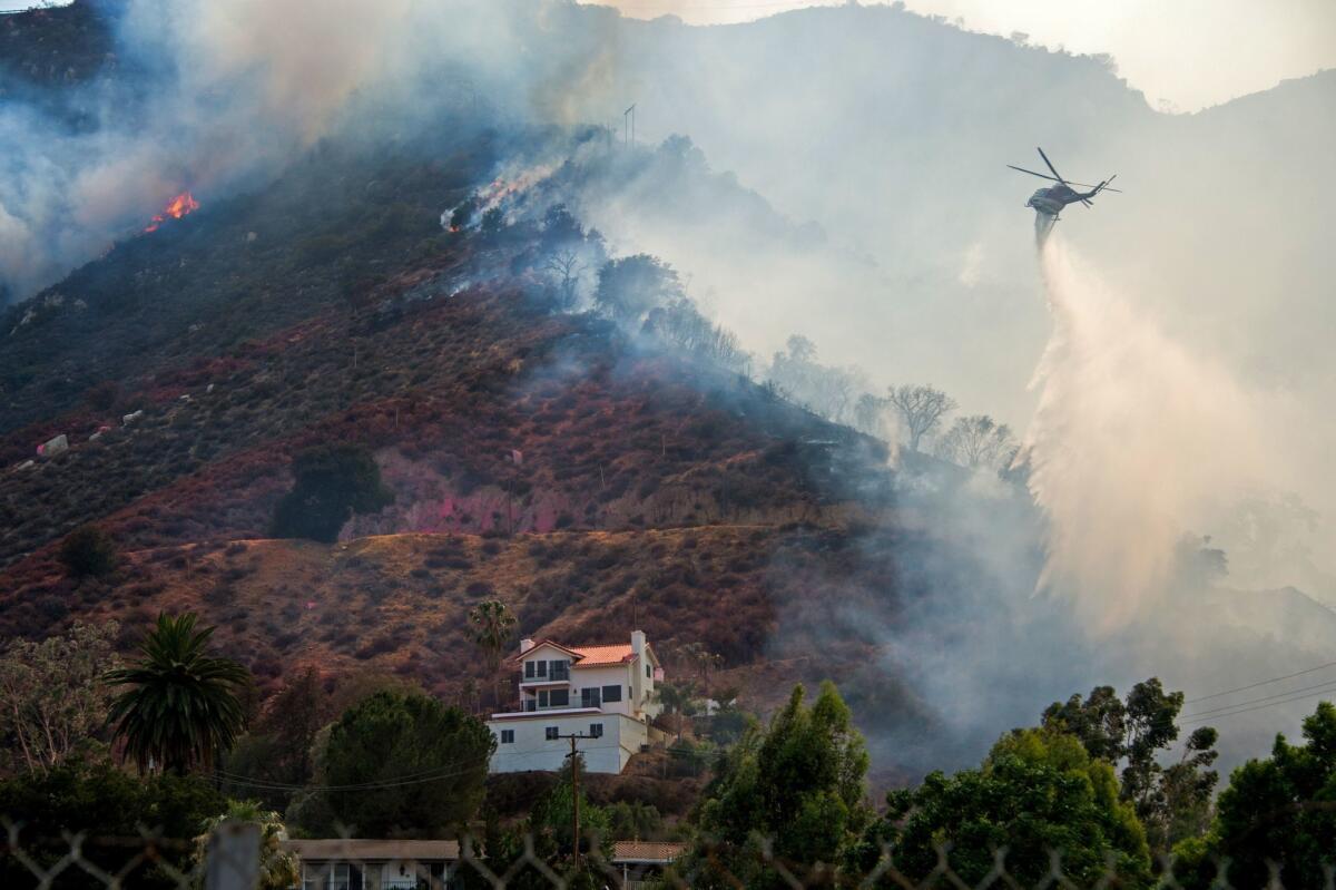 In this Aug. 10 photo, a helicopter drops water to protect a home from the Holy Fire in Lake Elsinore.