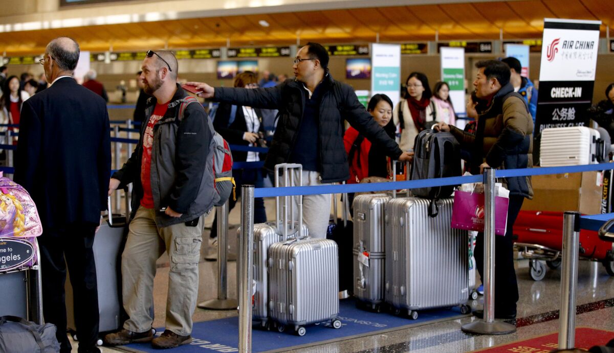 Travelers line up at the check-in counter for Air China inside the Bradley Terminal at Los Angeles International Airport. The number of flight searches by international travelers to the U.S. dropped after Trump's travel ban was adopted.