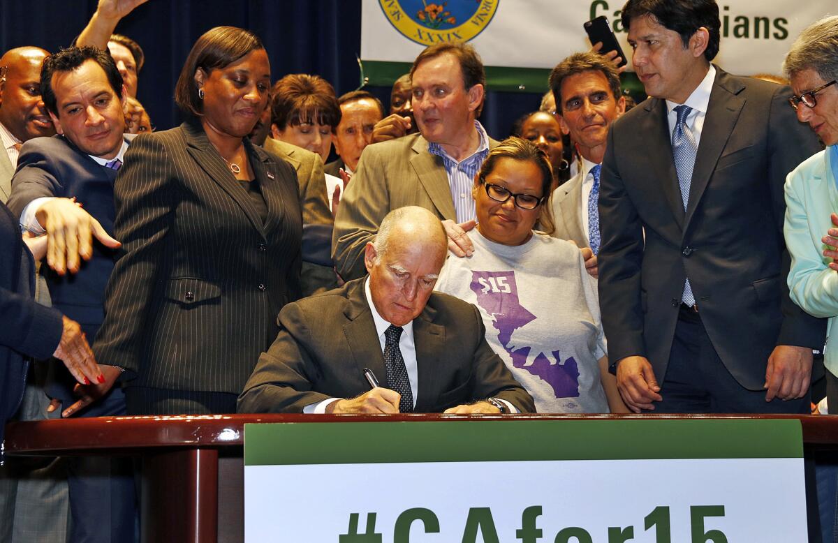 California Gov. Jerry Brown signs the minimum wage bill, raising the wage to $15 an hour by 2022. (Al Seib / Los Angeles Times)