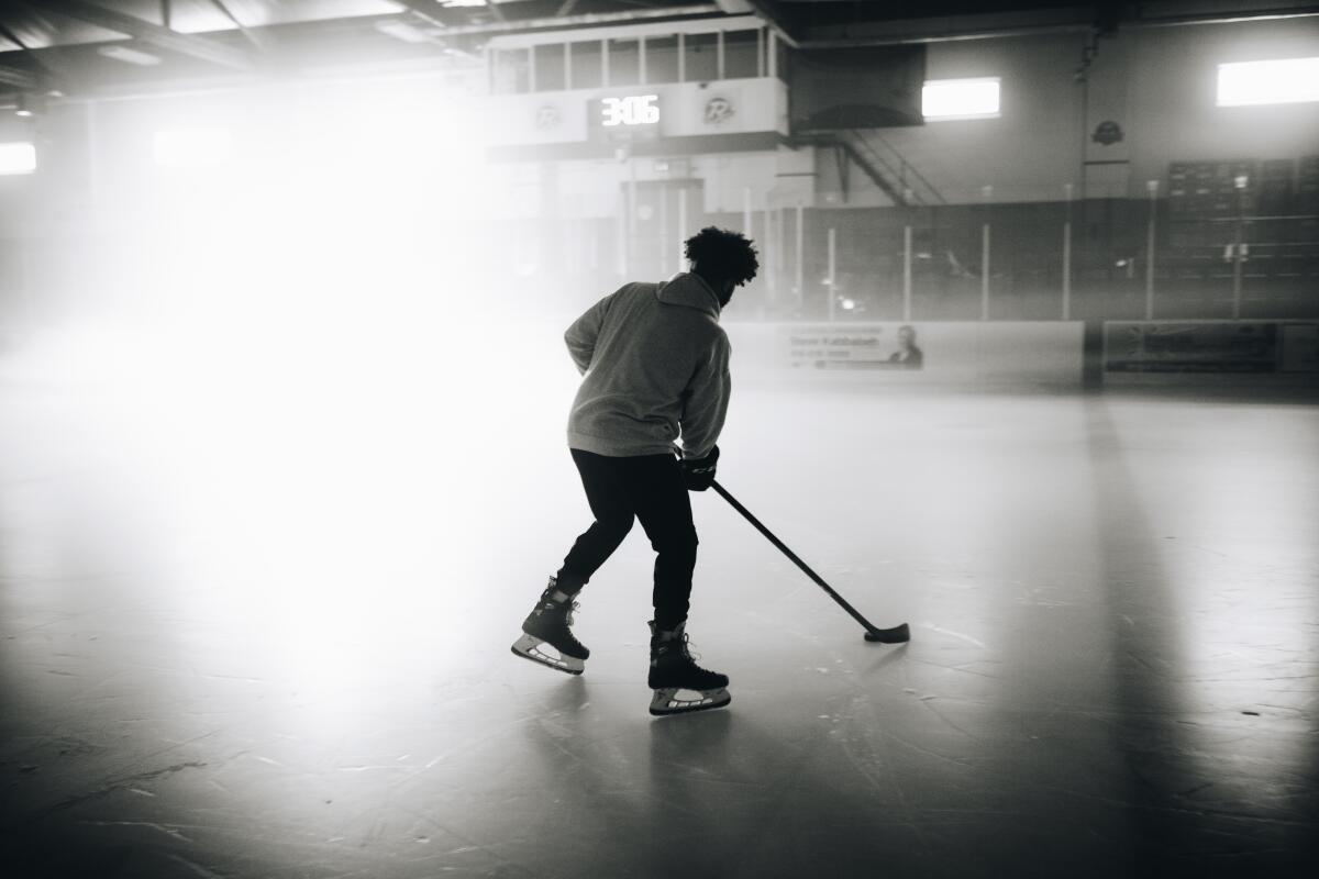 A Black hockey player skating on the ice, seen from behind