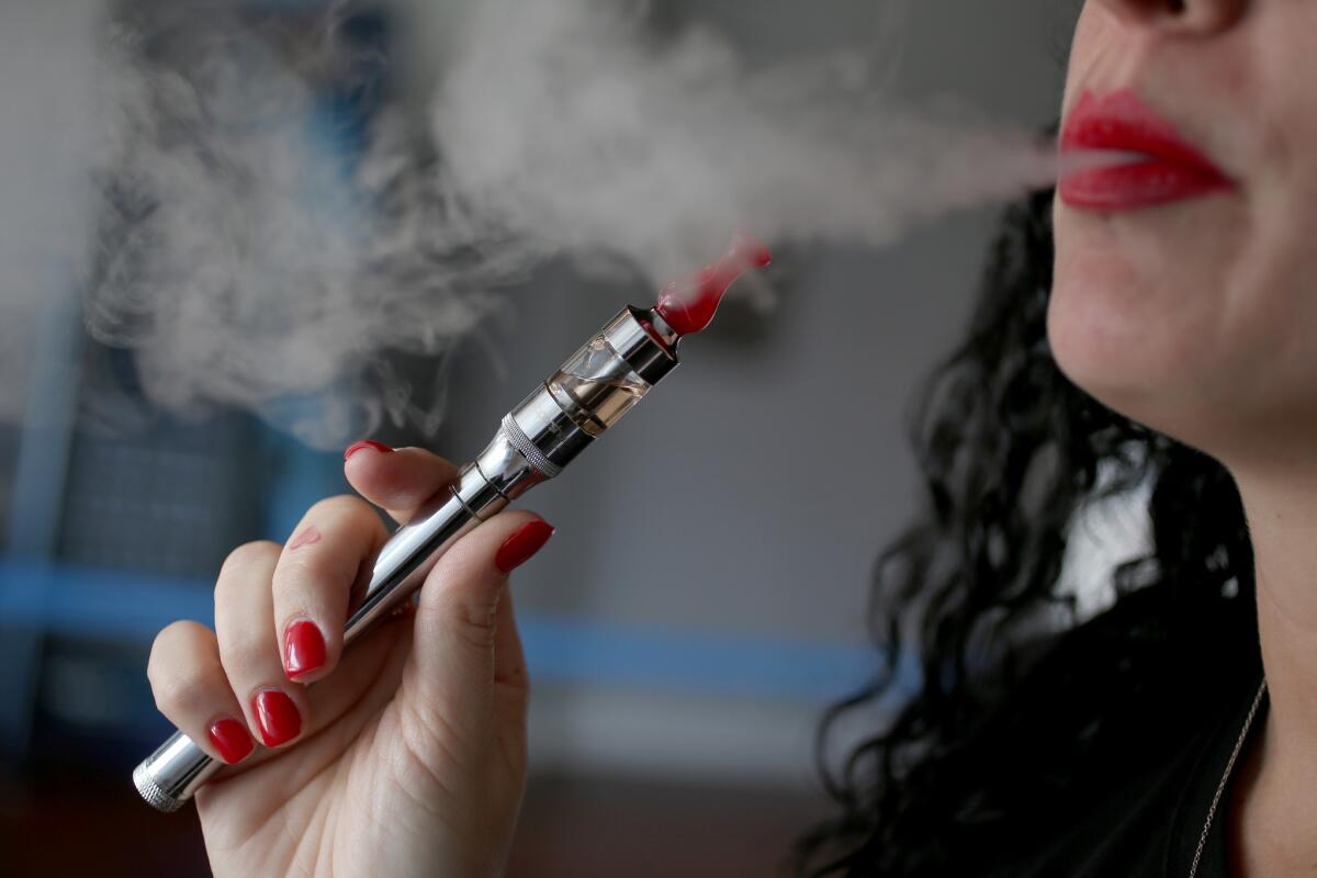 Julia Boyle smokes an electronic cigarette at the Vapor Shark store in Miami. The Federal Aviation Administration warns that e-cigarettes can spark fires in checked luggage on planes.