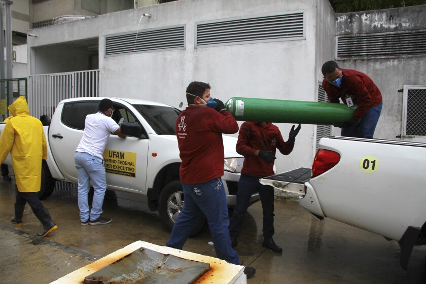 Amazonas Federal University's workers carry empty oxygen tanks at the Getulio Vargas Hospital amid the new coronavirus pandemic, Manaus, Brazil, Thursday, Jan. 14, 2021. Scores of COVID-19 patients in the Amazon rainforest's biggest city will be transferred out of state as the local health system collapses and dwindling stocks of oxygen tanks begin to falter. (AP Photos/Edmar Barros)