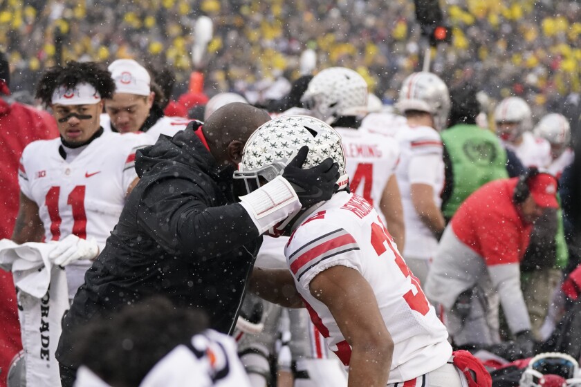 A staff member hugs Ohio State running back TreVeyon Henderson in the closing seconds of the second half of an NCAA college football game against Michigan, Saturday, Nov. 27, 2021, in Ann Arbor, Mich. (AP Photo/Carlos Osorio)