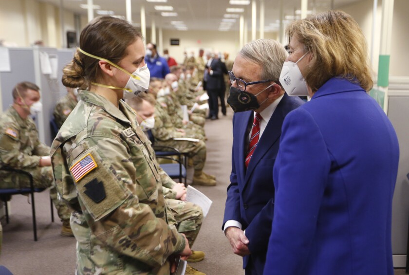 FILE - Ohio Gov. Mike DeWine, center, and his wife Fran, right, talk with specialist Emily Milosevic as they tour the Defense Supply Center Columbus in Columbus, Ohio, as members of the Ohio Army National Guard prepare to deploy to aid Ohio hospitals during the current surge in COVID-19 hospitalizations Jan. 6, 2022. Up to 40,000 Army National Guard soldiers across the country - or about 13% of the force — have not yet gotten the mandated COVID-19 vaccine, and as the deadline for shots looms, at least 14,000 of them have flatly refused and could be forced out of the service. (AP Photo/Paul Vernon, File)
