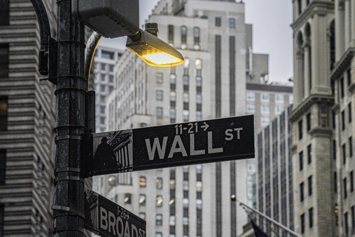 A Wall Street sign is below a street light.
