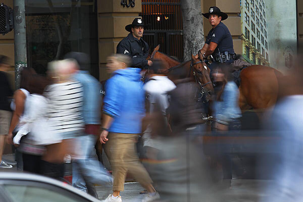 Police officers on horseback keep an eye on crowds and traffic in downtown Los Angeles in August 2011 at the first Art Walk following the death of an infant.
