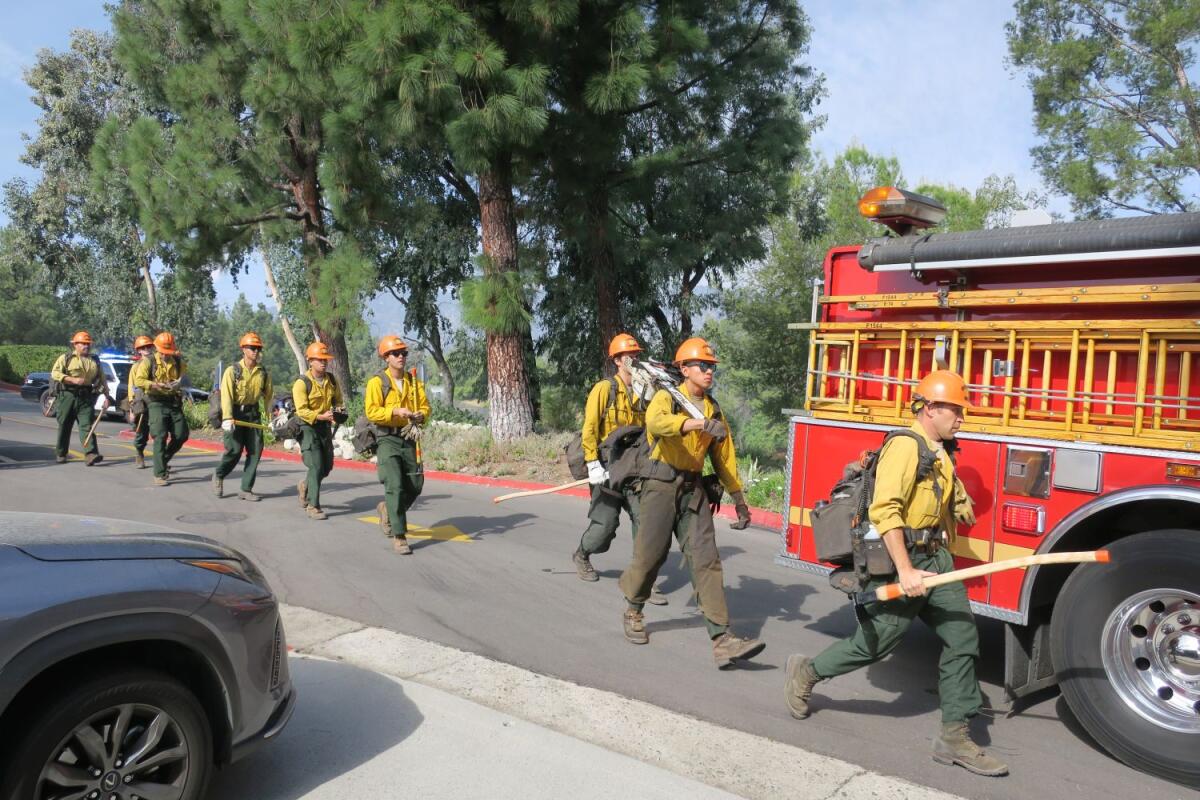 A crew with the Los Angeles County Fire Department heads toward a half-acre brush fire near the La Cañada Country Club Thursday, which came within mere feet of homes in Villa Cañada but was contained in just over one hour.
