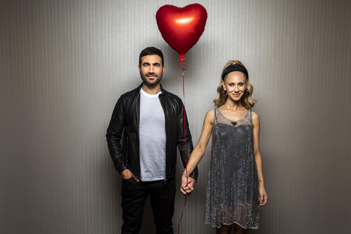 Actors Brett Goldstein and Juno Temple holds hands and a red balloon
