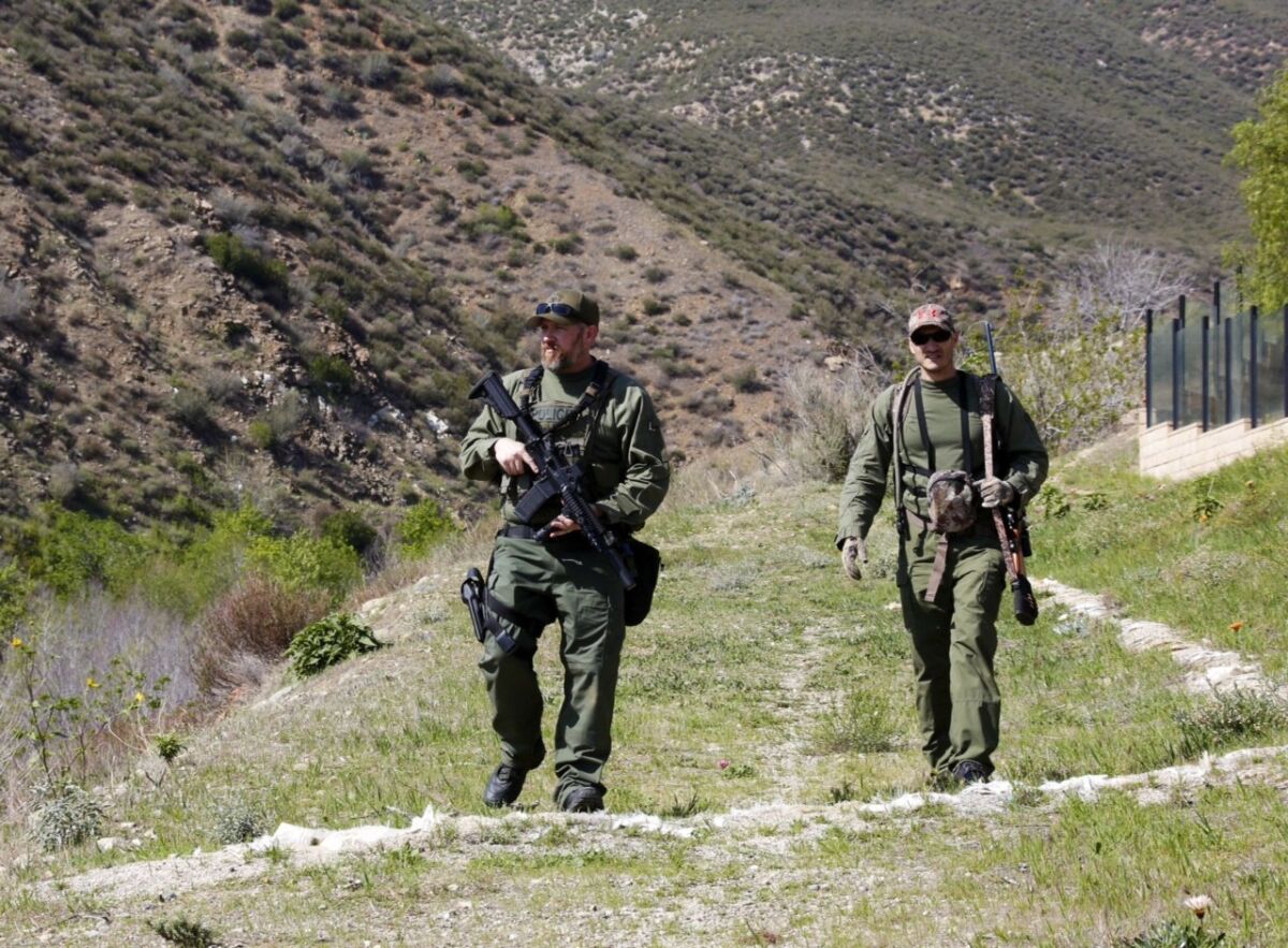 Inland Valley SWAT team members Cpl. Dills Tracy, left, and Marc Gonzales look for an aggressive mountain lion behind homes on 4100 block of Foxborough Dr. in Fontana.