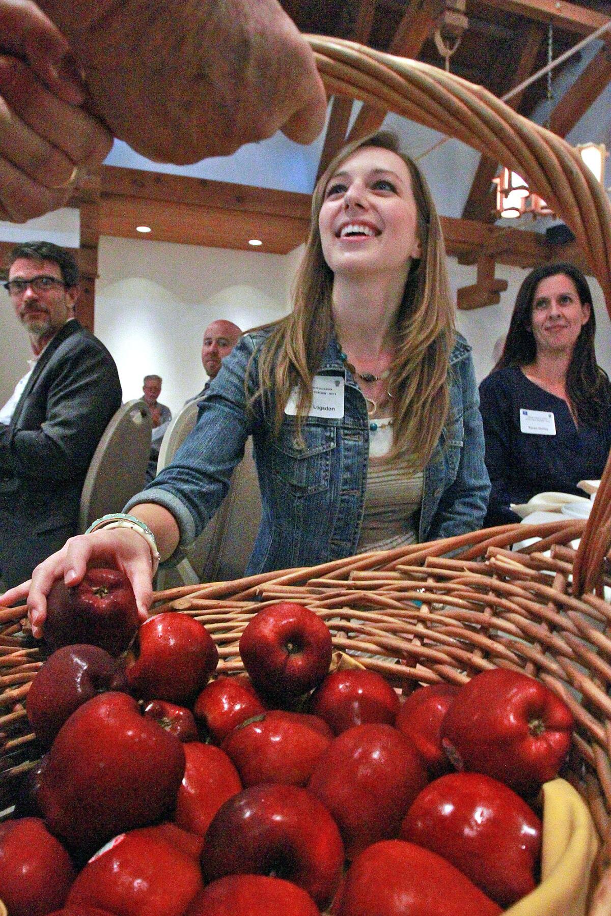 Alexis Logsdon, a new teacher at La Cañada Elementary School, picks a fresh red apple from a basket of apples at the Kiwanis Club of La Cañada Apple for a Teacher - 2014, at Descanso Gardens on Wednesday, August 6, 2014. New teachers at all the district's schools were introduced and offered an apple.