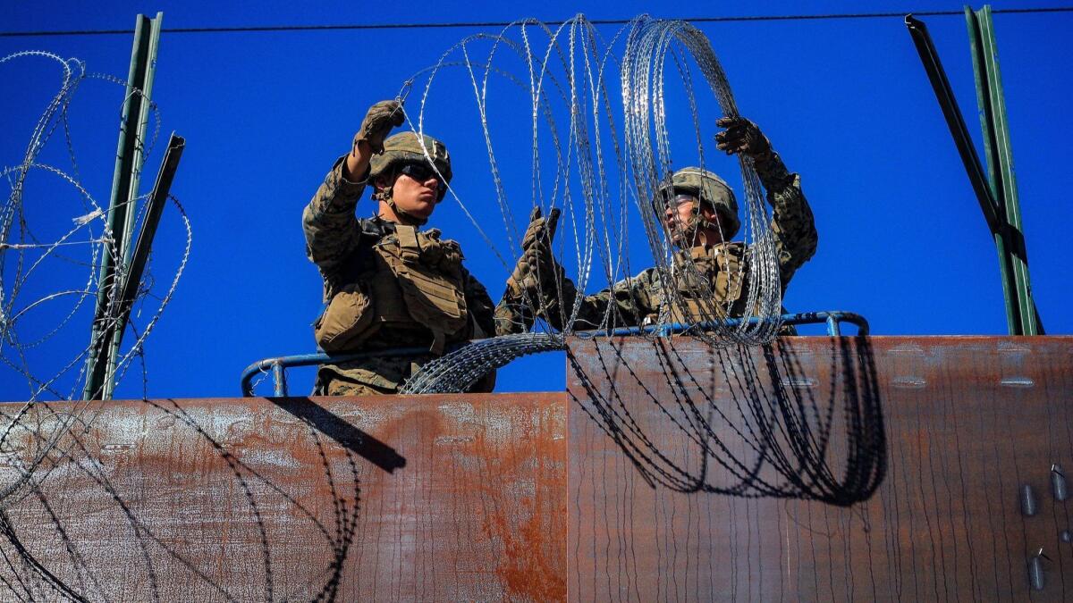 U.S. soldiers install barbed wire on the border with Mexico as seen from Colonia Libertad in Tijuana, Mexico, on Monday.