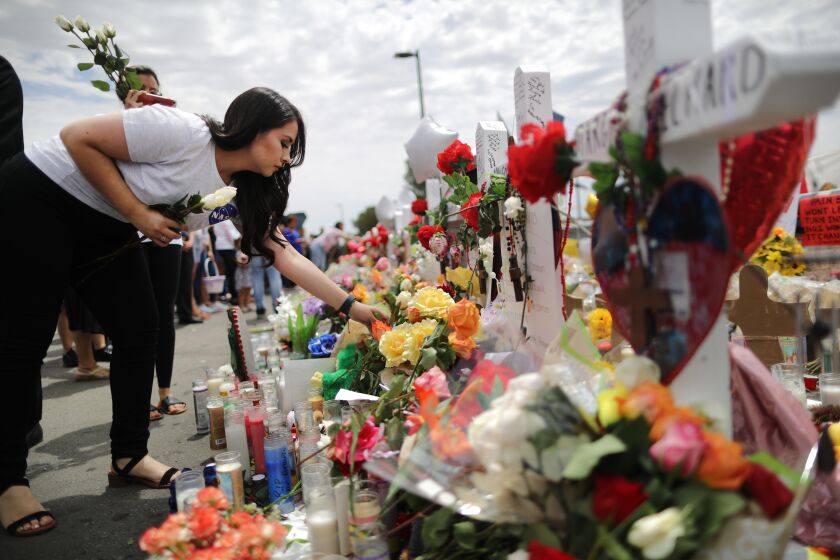 EL PASO, TEXAS - AUGUST 06: A woman places flowers at a makeshift memorial honoring victims outside Walmart, near the scene of a mass shooting which left at least 22 people dead, on August 6, 2019 in El Paso, Texas. A 21-year-old white male suspect remains in custody in El Paso which sits along the U.S.-Mexico border. President Donald Trump plans to visit the city August 7. (Photo by Mario Tama/Getty Images)